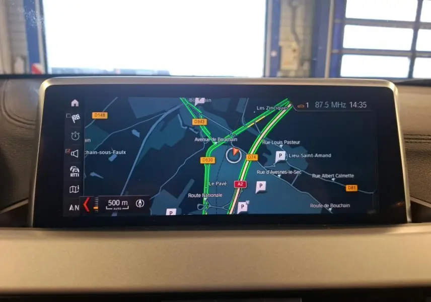 Écran central du GPS de BMW X2 blanc, affichant une carte routière avec itinéraire et trafic en temps réel.