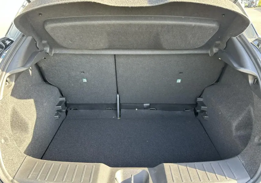 Coffre ouvert vu de l'arrière d'un Nissan Juke noir 2025, montrant l'espace de chargement vide et la garniture intérieure grise.