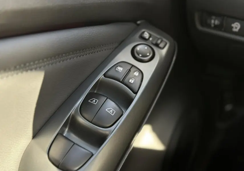 Gros plan sur les commandes des vitres et rétroviseurs côté conducteur du Nissan Juke noir 2025.