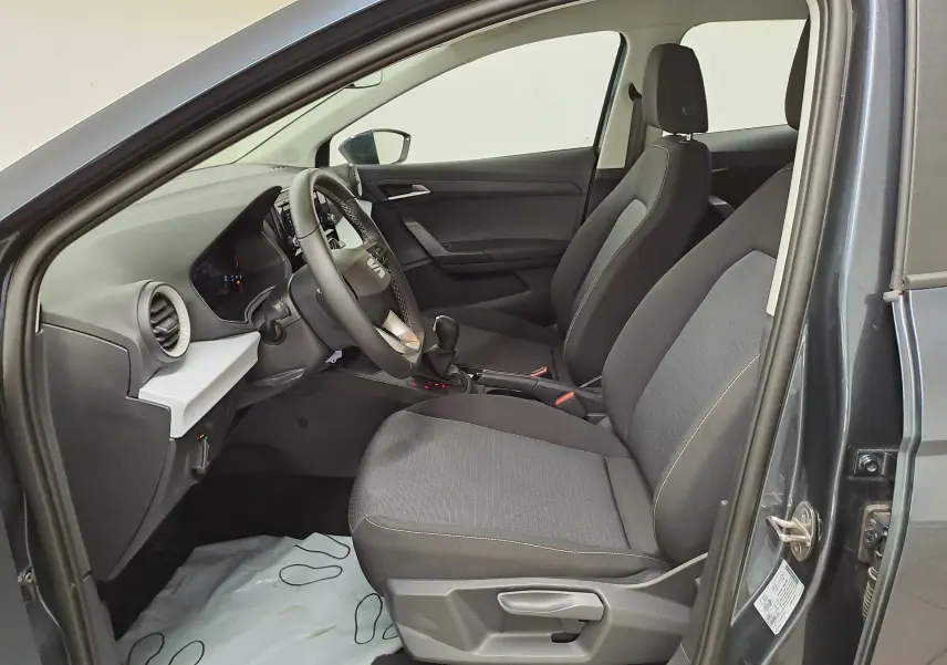 Vue intérieure côté conducteur de la SEAT IBIZA 1.0 TSI 115 DSG7 COPA gris magnétique, sièges tissu noirs et tableau de bord moderne.