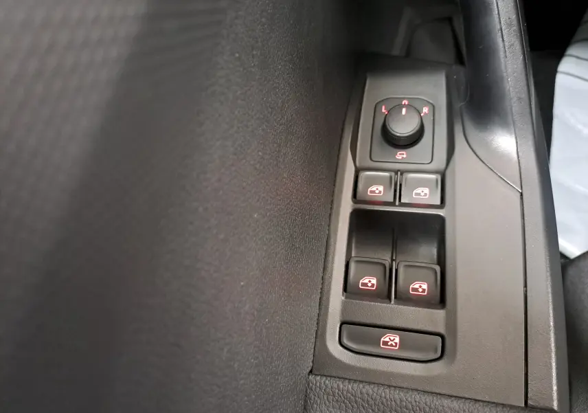 Gros plan sur les commandes des vitres électriques et réglage des rétroviseurs côté conducteur d'une SEAT Ibiza gris magnétique.