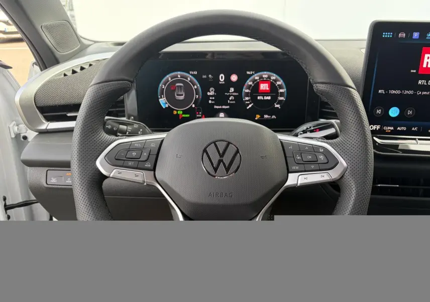 Vue rapprochée du volant multifonction en cuir noir du Volkswagen T-Roc avec tableau de bord numérique et écran central tactile.