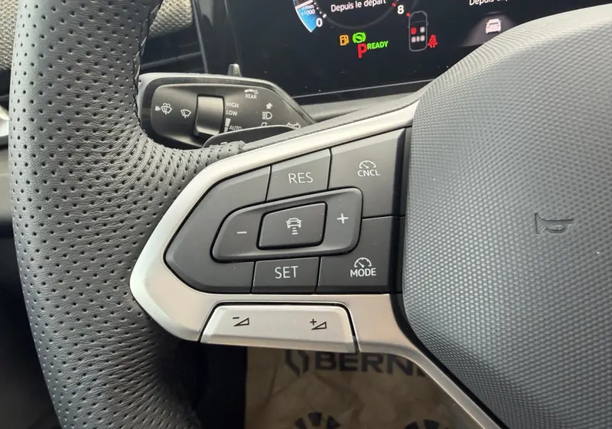 Gros plan sur le volant multifonction cuir du Volkswagen T-Roc 2026, boutons de régulateur de vitesse et tableau de bord numérique.