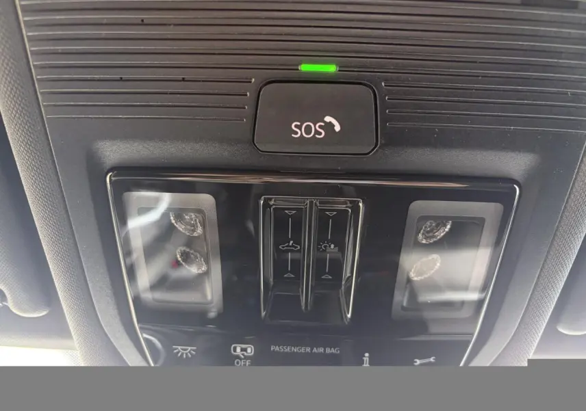 Vue rapprochée du panneau de commande intérieur au plafond du Volkswagen T-Roc blanc, avec bouton SOS et commandes d’éclairage.