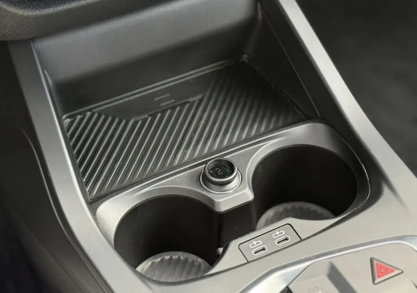 Gros plan sur la console centrale noire de la BMW Série 1 118d M Sport, avec porte-gobelets et prises USB-C visibles.