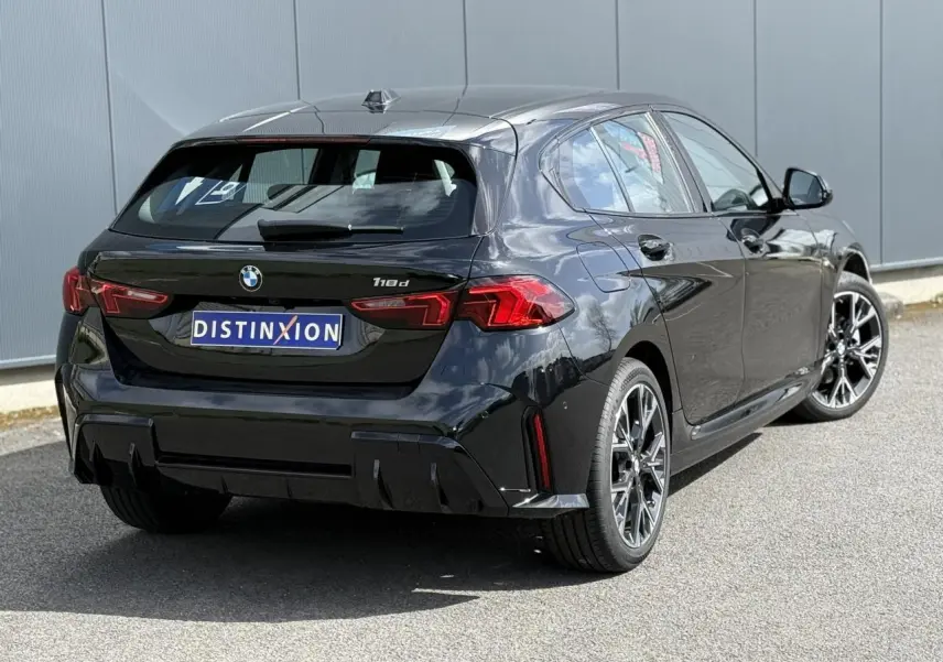 Vue 3/4 arrière droite d'une BMW Série 1 118d M Sport Saphirschwarz avec jantes alliage 18 pouces et feux LED.