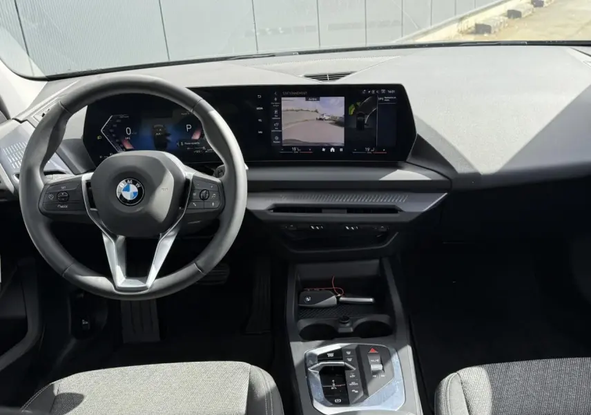 Vue intérieure avant de la BMW Série 1 118d M Sport 2025, tableau de bord noir et sièges tissu anthracite.