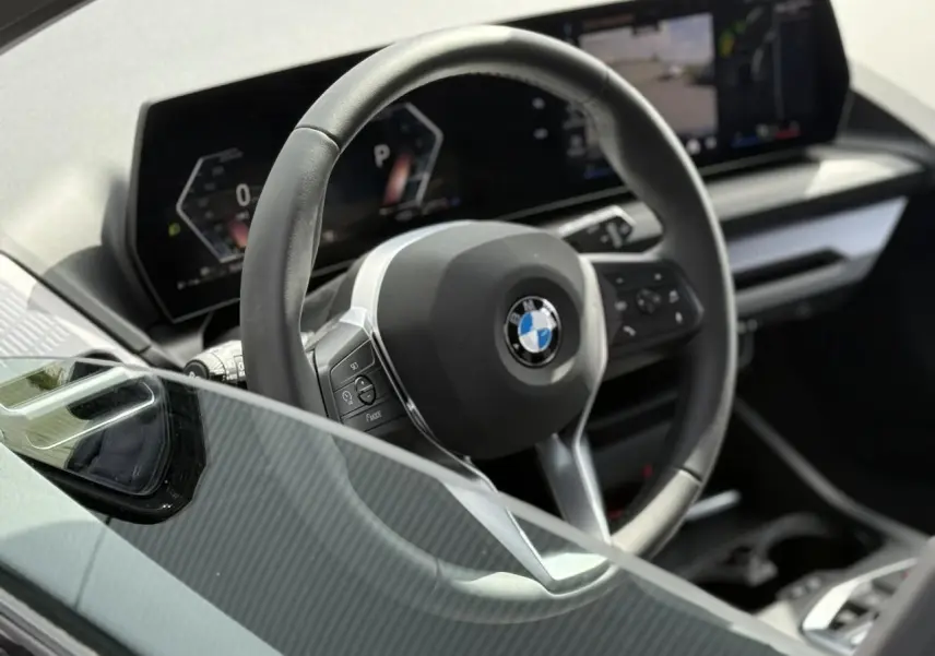 Vue rapprochée du volant multifonctions noir et du tableau de bord numérique de la BMW Série 1 118dA 2025.