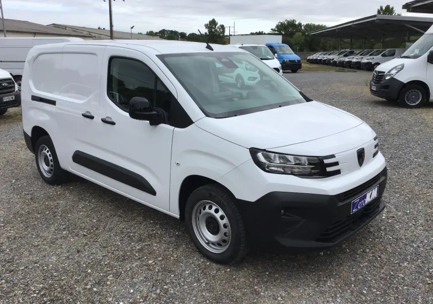 Peugeot Partner blanc en vue 3/4 avant droit, fourgon utilitaire avec protections noires et jantes acier.