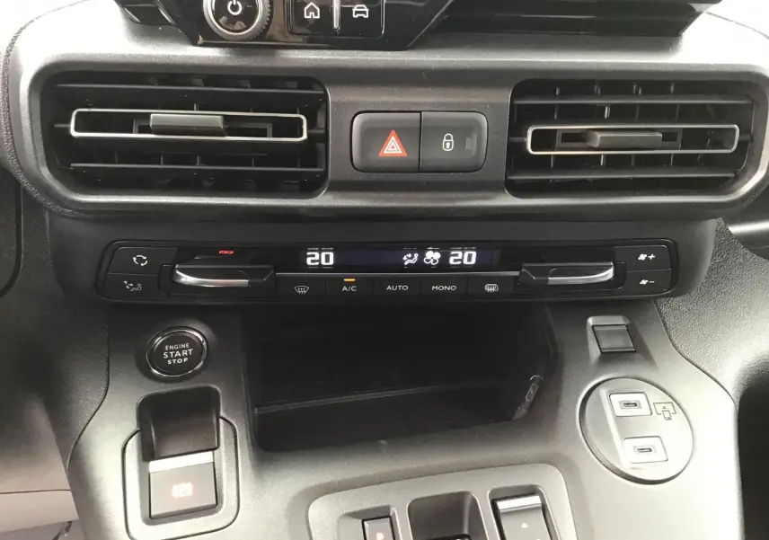 Vue rapprochée du tableau de bord du Peugeot Partner blanc 2026, montrant la climatisation digitale et le bouton start/stop.