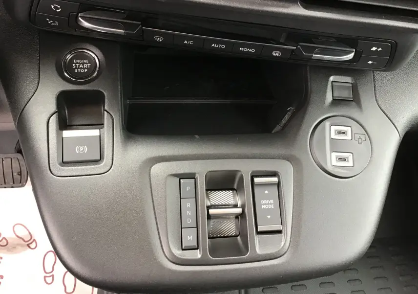 Vue rapprochée du tableau de bord central du Peugeot Partner blanc, montrant les commandes de climatisation, démarrage et modes de conduite.