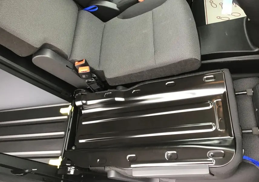 Vue rapprochée de la banquette arrière rabattue du Peugeot Partner XL blanc, montrant le plancher métallique et les sièges gris.