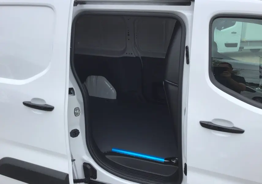 Vue latérale gauche du Peugeot Partner blanc avec porte coulissante ouverte montrant l’espace de chargement vide.