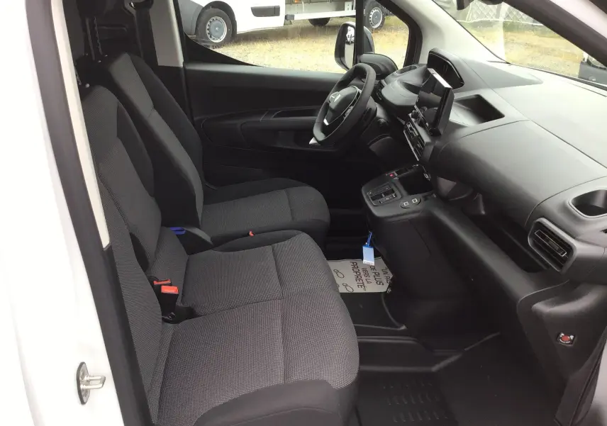 Vue intérieure côté conducteur du Peugeot Partner blanc 2026, montrant les sièges avant et le tableau de bord moderne.