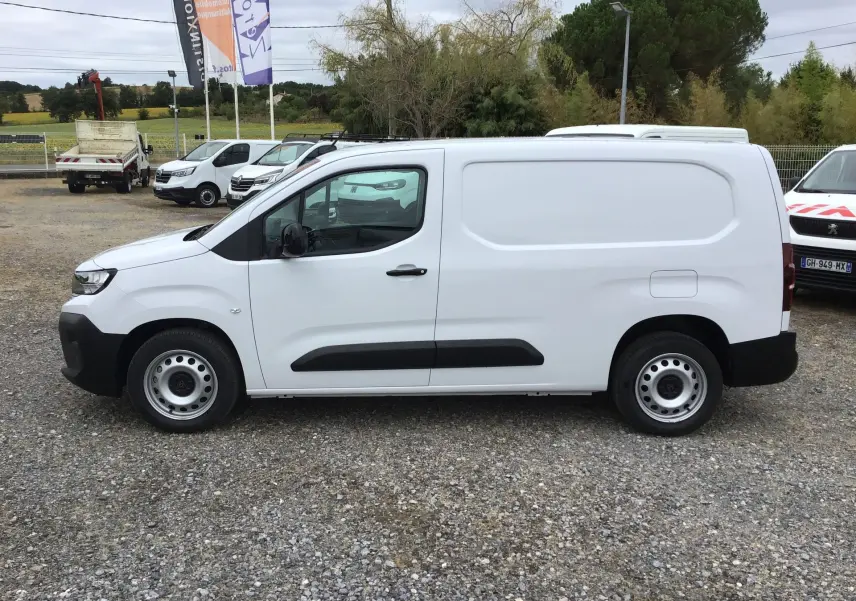 Vue de profil côté gauche d’un utilitaire Peugeot Partner blanc 2026 avec porte latérale coulissante et jantes acier.