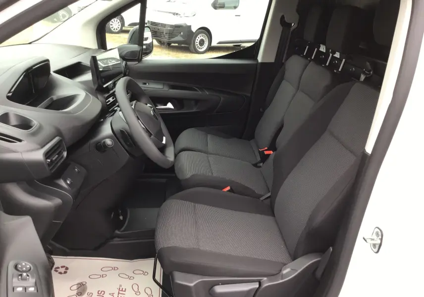 Vue intérieure côté conducteur du Peugeot Partner blanc 2026, montrant les sièges avant et le tableau de bord moderne.