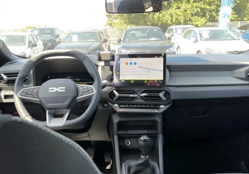 Vue intérieure avant du tableau de bord gris et volant multifonction du Dacia Bigster 2026 avec écran tactile et boîte manuelle.