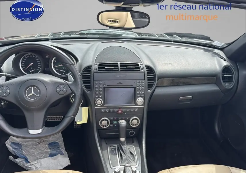Vue intérieure du tableau de bord et console centrale d'une Mercedes SLK 55 AMG 7G-Tronic de 2009 avec sellerie cuir beige et volant noir.