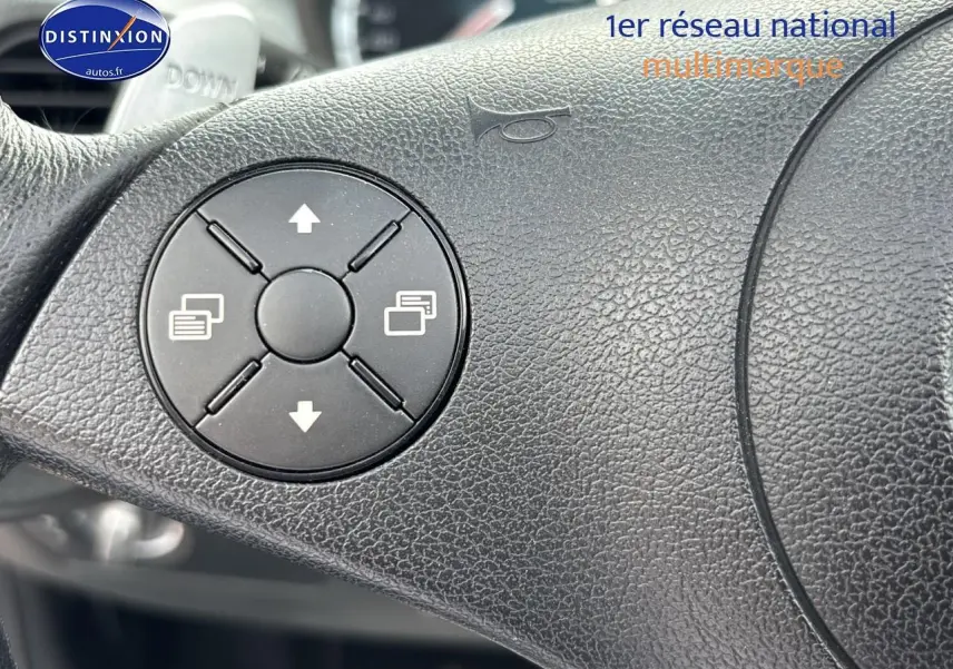 Gros plan sur le volant en cuir noir du Mercedes SLK 55 AMG 7G-Tronic de 2009, montrant les commandes intégrées.