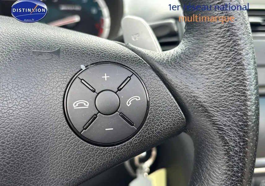 Gros plan sur le volant en cuir noir de la Mercedes SLK 55 AMG 7G-Tronic de 2009 avec commandes intégrées.