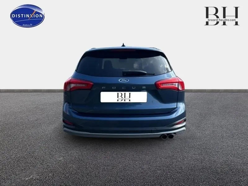 Vue arrière d'une Ford Focus bleu azur métallisé de 2019 avec double sortie d'échappement et vitres arrière surteintées.