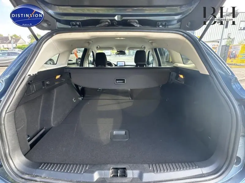 Vue arrière du coffre ouvert d'une Ford Focus bleu azur métallisé, montrant l'espace et la plage arrière rétractable.