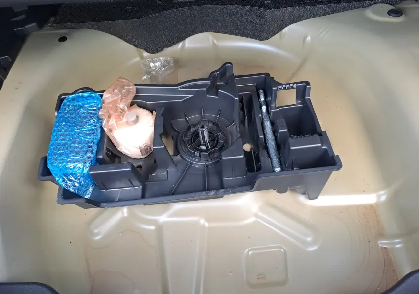 Vue rapprochée du rangement sous le coffre d'une Citroën C4 2025 Manhattan Green, sans roue de secours visible.