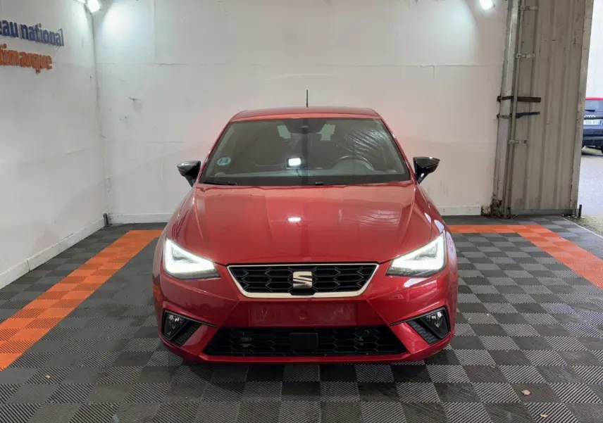Vue de face d'une SEAT IBIZA 1.0 TSI 110 FR rouge avec phares LED allumés dans un garage.