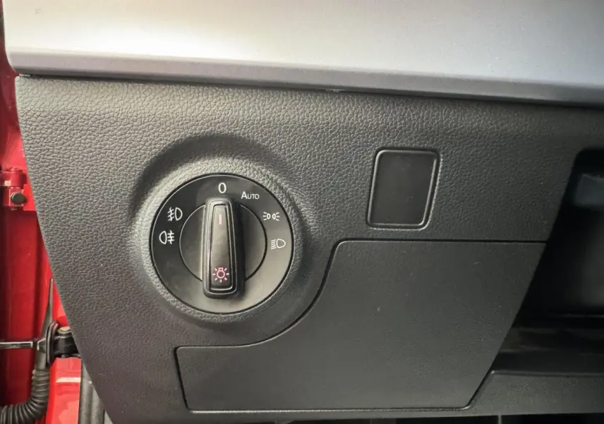 Gros plan sur le bouton de commande des phares dans l'habitacle noir d'une SEAT IBIZA rouge 2024.