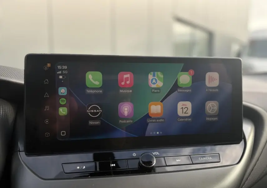 Écran tactile central affichant Apple CarPlay dans l'habitacle du Nissan Juke 2025, vue de face.