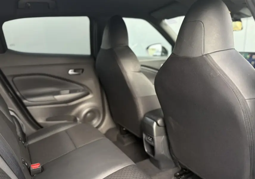 Vue intérieure arrière du Nissan Juke 2025, sièges noirs en tissu et cuir synthétique, avec port USB central visible.