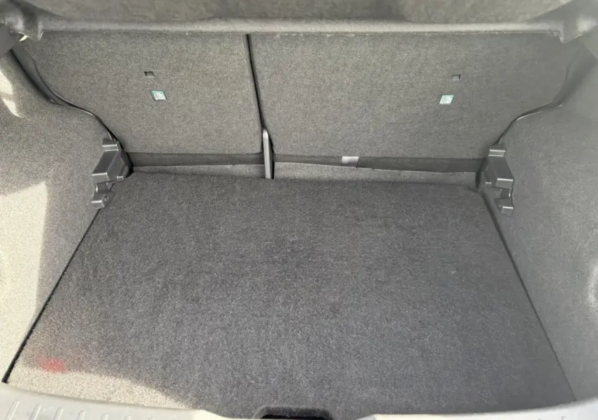 Coffre modulable du Nissan Juke 2025 en vue intérieure, revêtement gris foncé uniforme et propre.