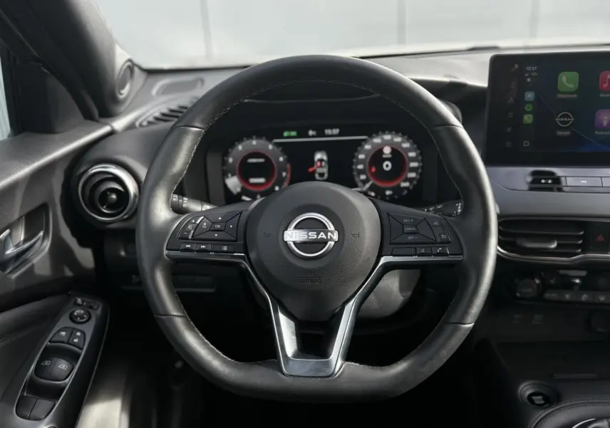 Vue rapprochée du volant en cuir noir du Nissan Juke 2025 avec tableau de bord digital et écran tactile.