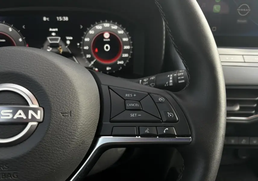 Gros plan sur le volant cuir noir côté droit du Nissan Juke 2025 avec commandes de régulateur de vitesse et tableau de bord digital.