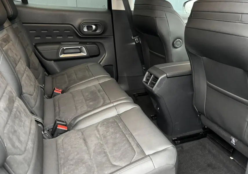 Vue intérieure arrière du Citroën C5 Aircross 2025, sièges en Alcantara noir avec surpiqûres bleues et console centrale.