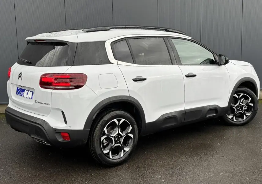 Vue 3/4 arrière droite du Citroën C5 Aircross blanc Okénite avec toit noir et protections latérales noires.