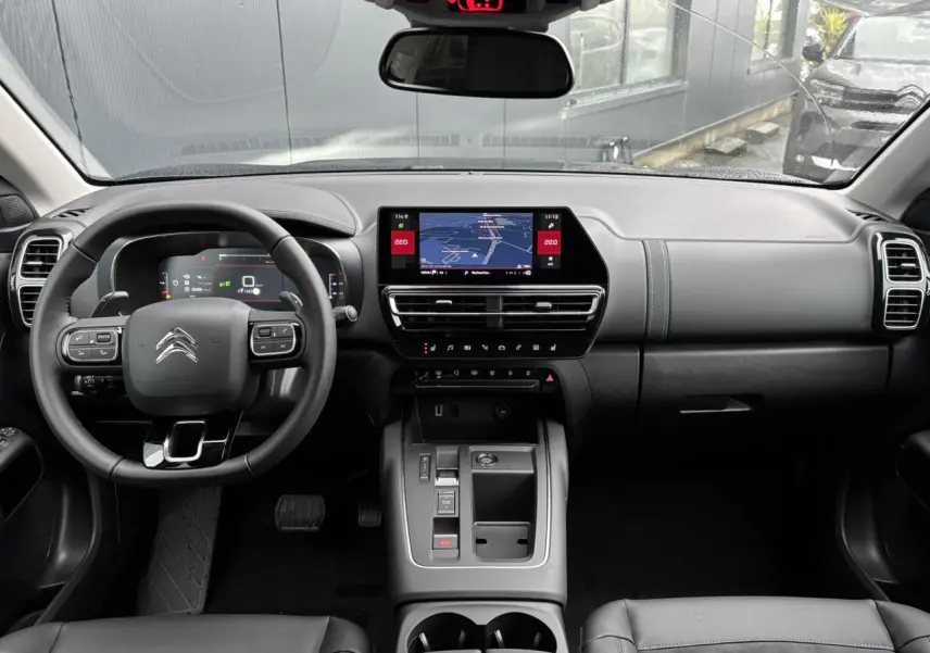 Vue intérieure avant du Citroën C5 Aircross 2025, tableau de bord noir avec écran tactile central et volant multifonction.