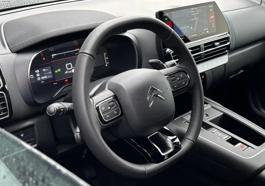 Vue intérieure du poste de conduite du Citroën C5 Aircross blanc, avec volant cuir et écran tactile central.