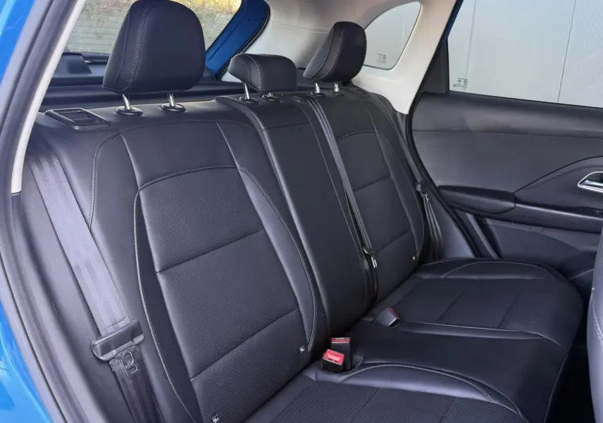 Vue intérieure de la banquette arrière en tissu et similicuir noir du MG Motor ZS 1.5 Hybrid+ 197 Luxury, porte bleu Como ouverte.