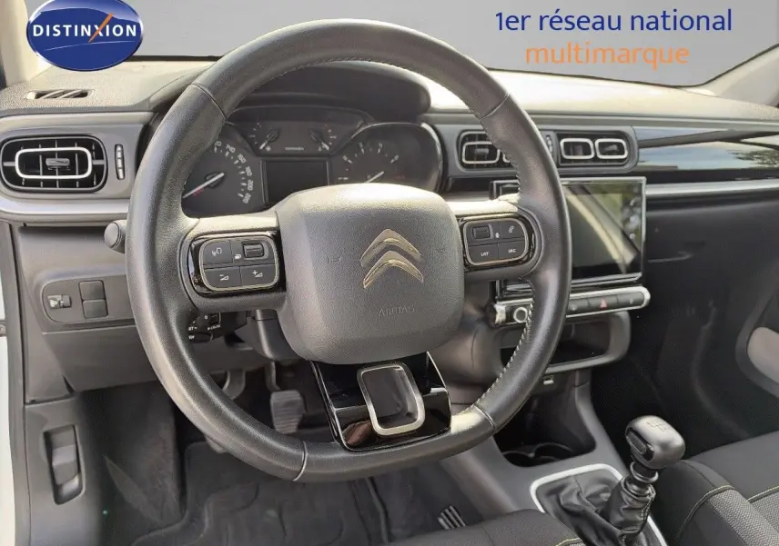 Intérieur de la Citroën C3 2021 vue du poste de conduite, volant cuir, tableau de bord noir et levier de vitesse manuel.