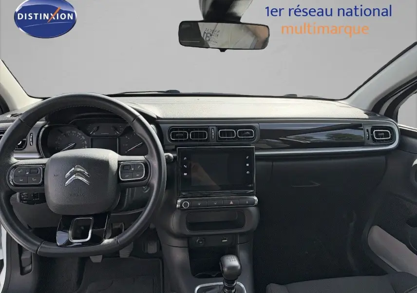 Vue intérieure frontale du tableau de bord noir et volant de la Citroën C3 blanche 2021 avec boîte manuelle.
