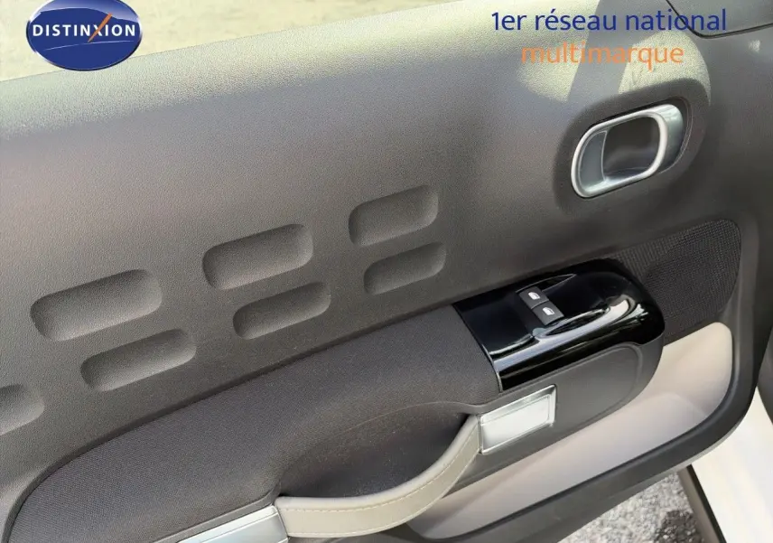 Détail de la porte avant gauche de la Citroën C3 blanche 2021, avec commandes de vitres et poignée intégrée.