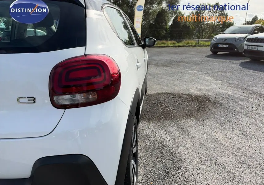 Vue 3/4 arrière droite d'une Citroën C3 blanche de 2021 avec feux arrière distinctifs et protections noires.