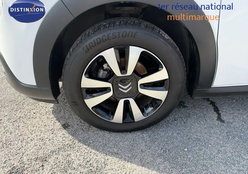 Gros plan sur la roue avant droite d'une Citroën C3 blanche de 2021 avec jante alliage bicolore et pneu Bridgestone.