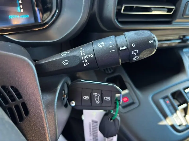 Gros plan sur la commande d'essuie-glace et la clé insérée dans le contacteur du tableau de bord noir du Citroën Berlingo Fourgon.