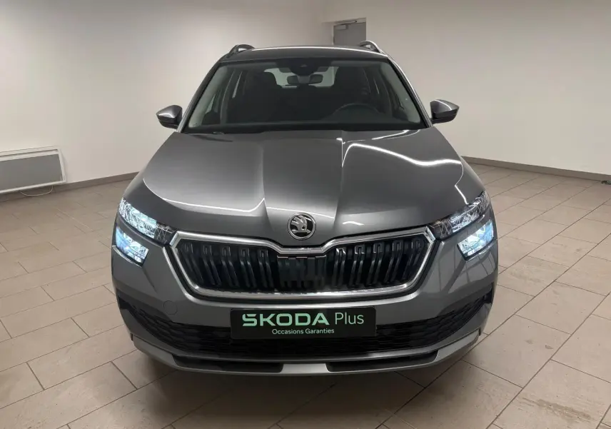 Vue avant d'un Skoda Kamiq 2023 gris graphite avec calandre noire et phares allumés en intérieur.