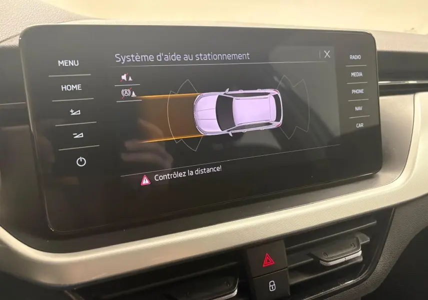 Écran central du Skoda Kamiq 2023 montrant le système d'aide au stationnement avec interface claire et boutons tactiles.