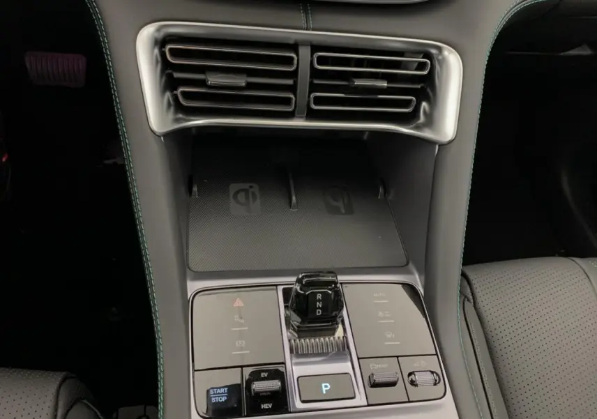 Vue rapprochée de la console centrale du BYD SEAL U 1.5 DM-i 2025, avec boîte auto et surface de charge sans fil noire.