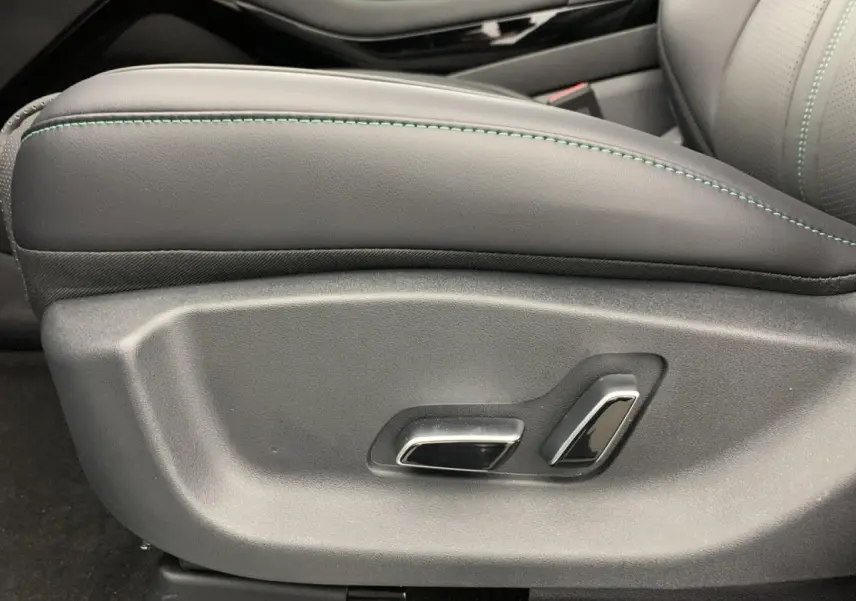Détail des commandes électriques du siège avant côté gauche en cuir noir avec surpiqûres vertes du BYD SEAL U 2025.