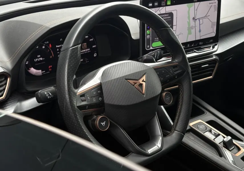 Vue rapprochée du volant cuir perforé noir avec logo CUPRA cuivré et tableau de bord numérique du Formentor 2025.